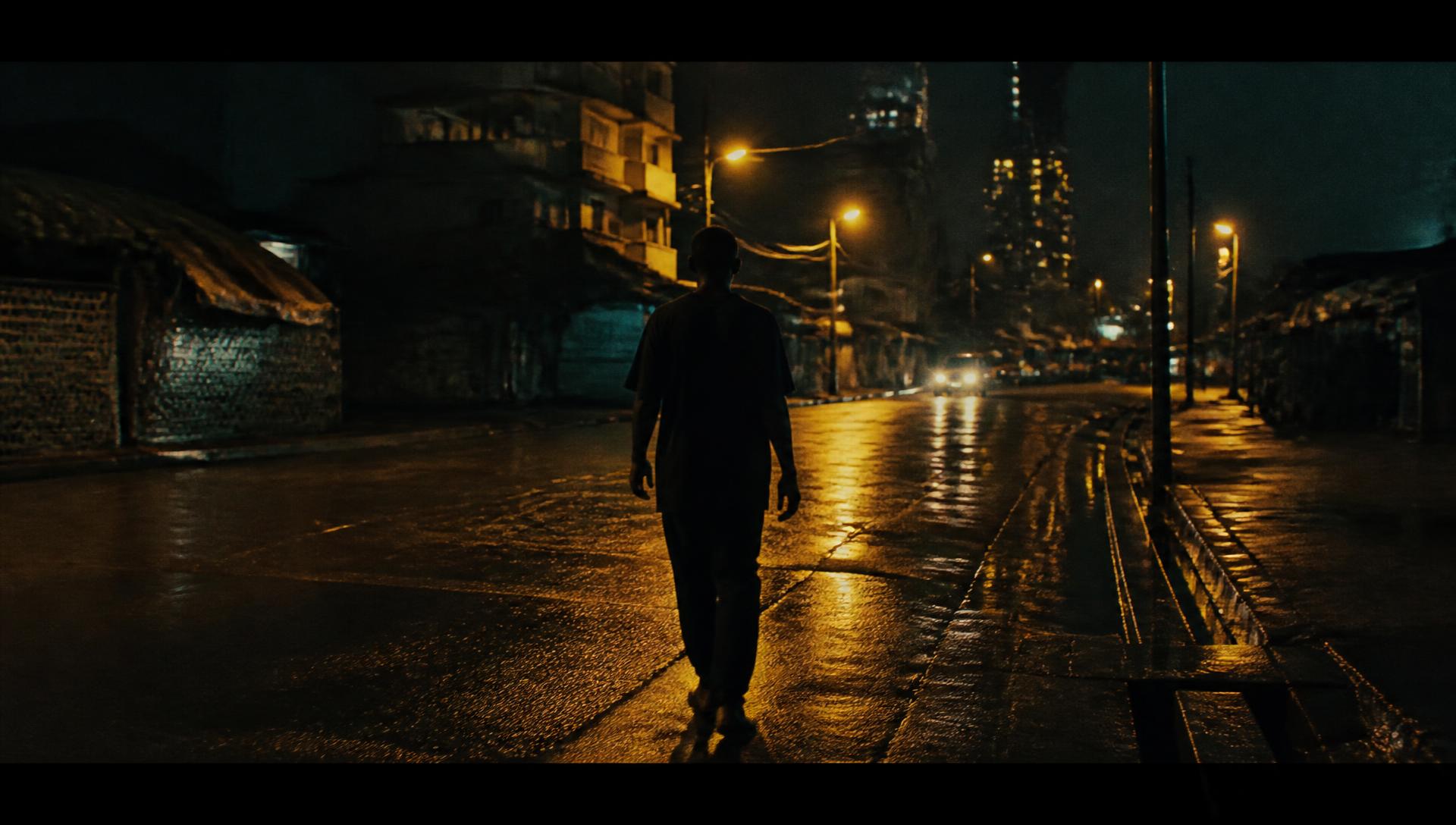 Lagos street at night under amber light, a lone figure walking